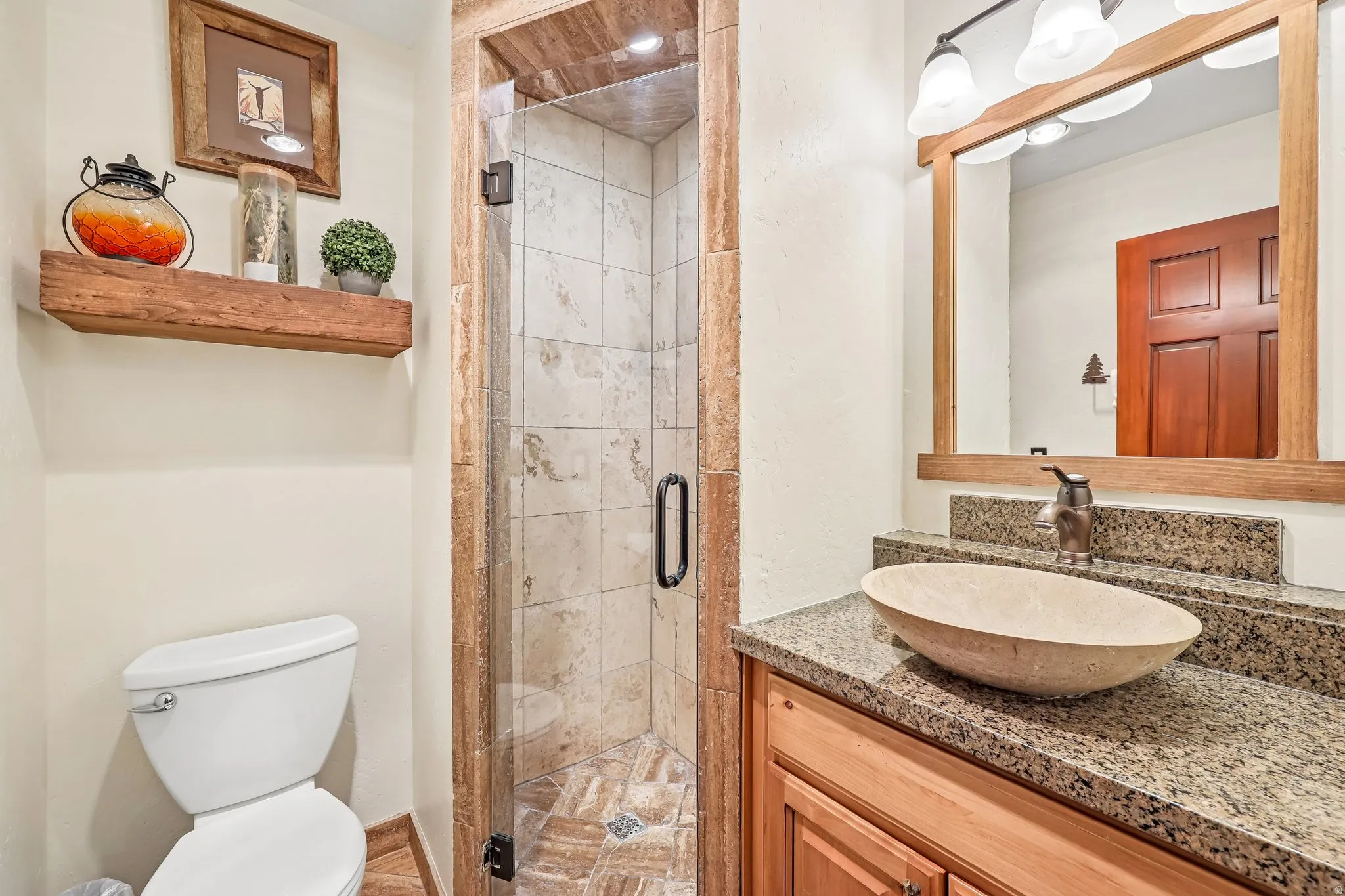 Walk-in shower with clear glass enclosure and stone tile surround