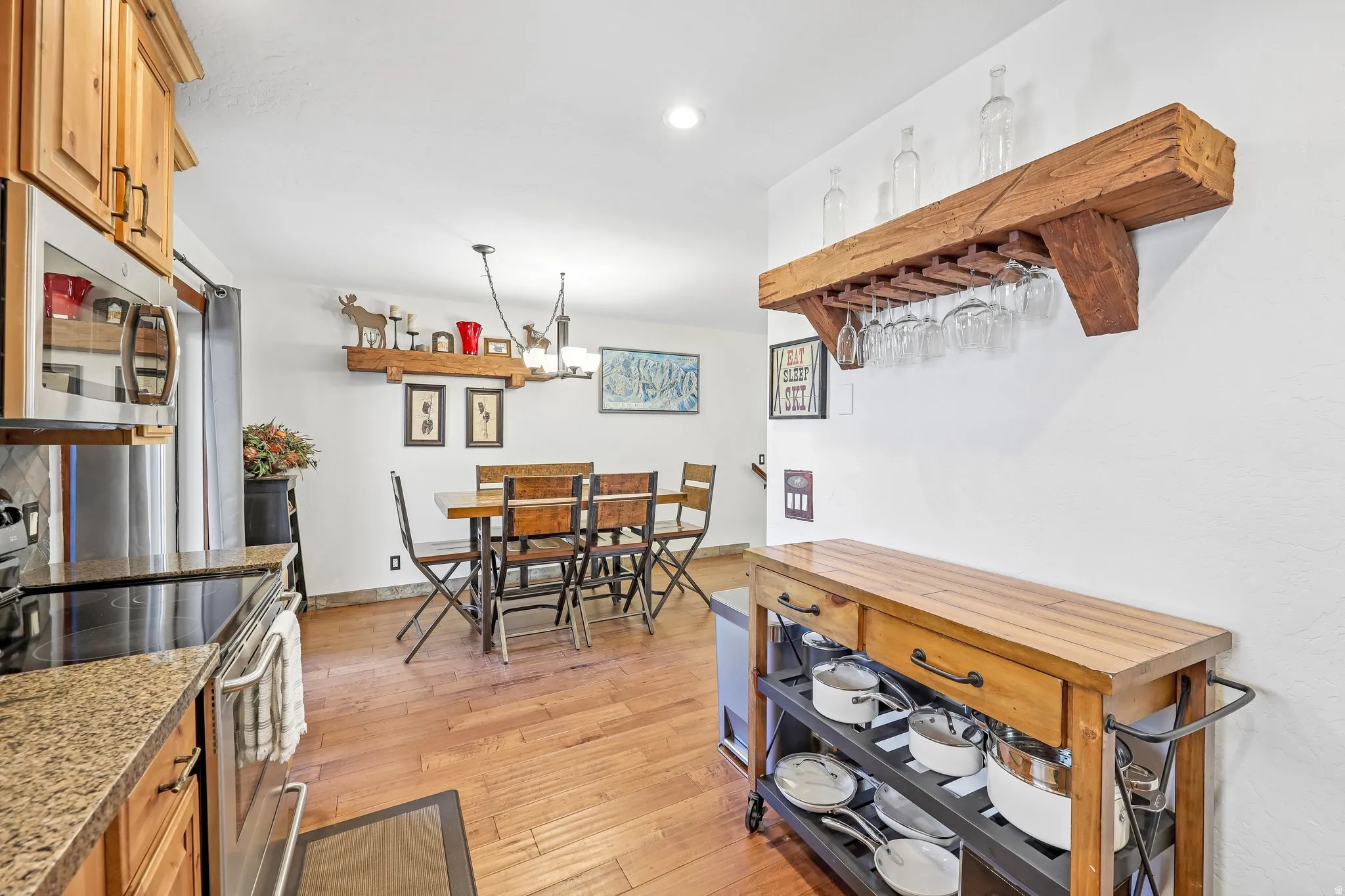 Kitchen and dining area featuring wood-finish flooring, light cabinetry, and granite-look countertops