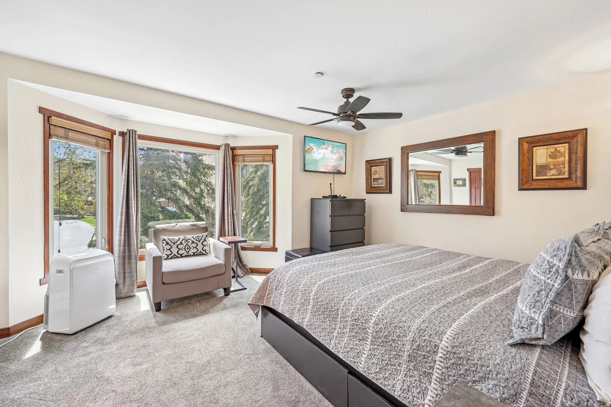 Bay window with wood trim, ceiling fan, and carpeted flooring