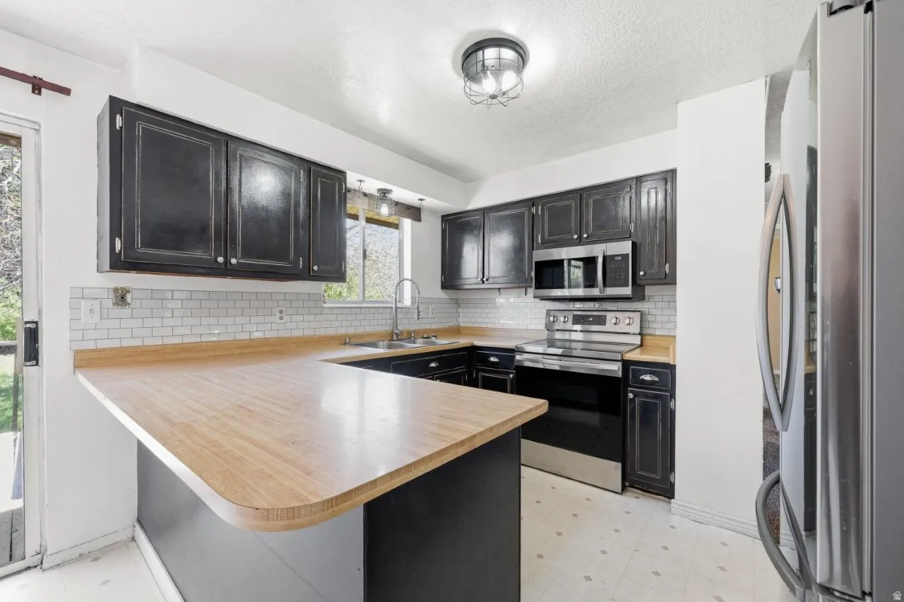 Kitchen details shine here with distressed dark cabinetry, white subway tile backsplash, and a full stainless steel appliance package. Plenty of cabinet storage and counter space for the home cook ready to make this kitchen their own.