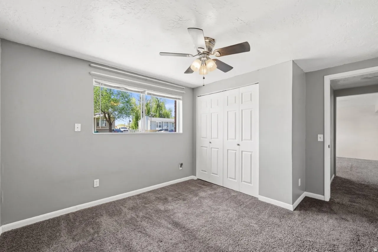 Another angle of the updated bedroom showcasing the double door closet, ceiling fan, and open doorway into the hall. Clean and ready for you to make it yours.