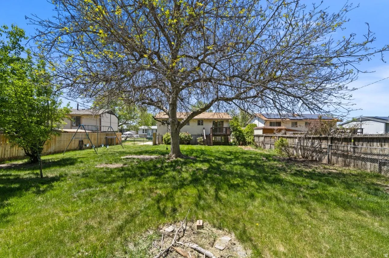 Spacious fully fenced backyard with a large shade tree, swing set, back deck with stairs, and room to roam. A fantastic outdoor space for kids, pets, and entertaining.
