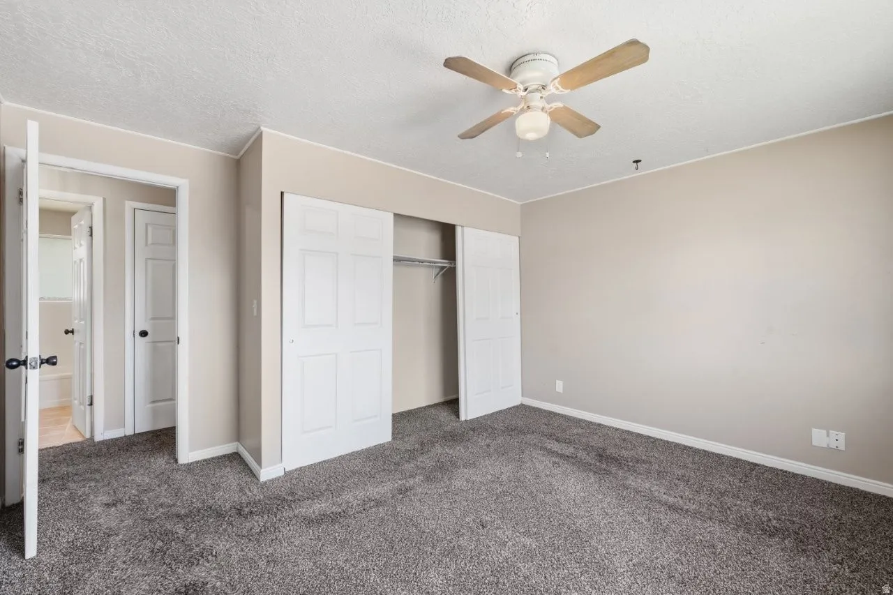 Spacious primary bedroom features a double sliding door closet, ceiling fan, and direct access to the hallway bath. Clean, neutral tones and carpet throughout make this a comfortable retreat.