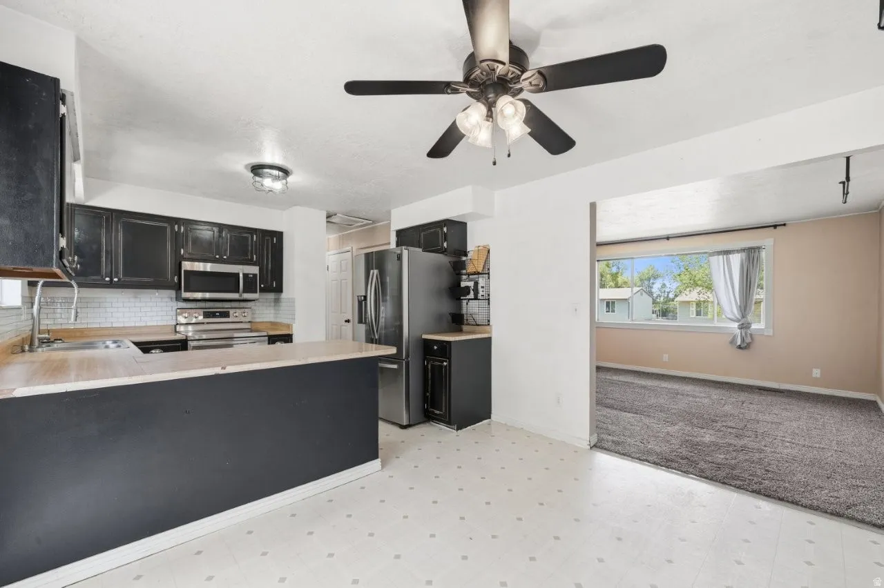 Great kitchen layout with stainless steel appliances including a refrigerator, range, and microwave, plus a peninsula and sight lines into the living room. The open flow between spaces makes everyday living easy and functional.