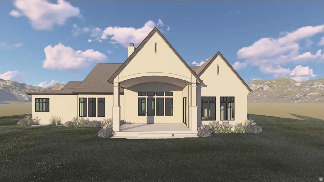 Back of house with a mountain view, stucco siding, and a lawn