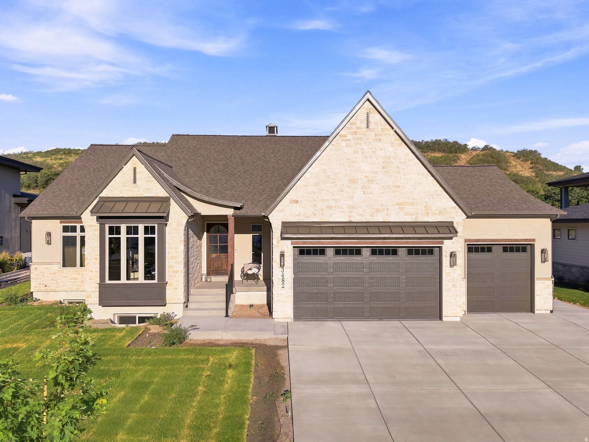 Stone and stucco exterior with a brown shingle roof