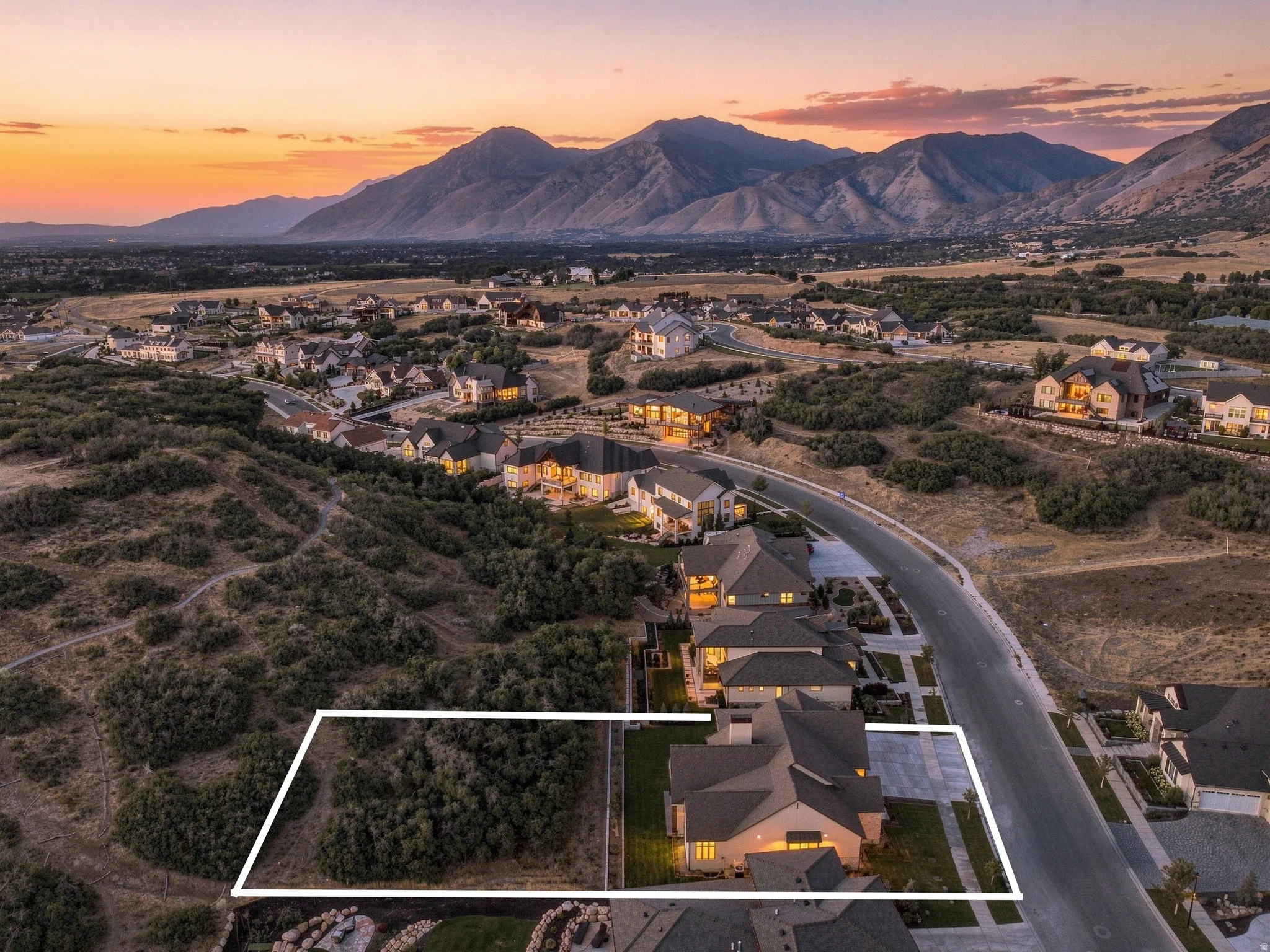 Mountain backdrop, suburban setting, paved road, established residential area, expansive natural landscaping