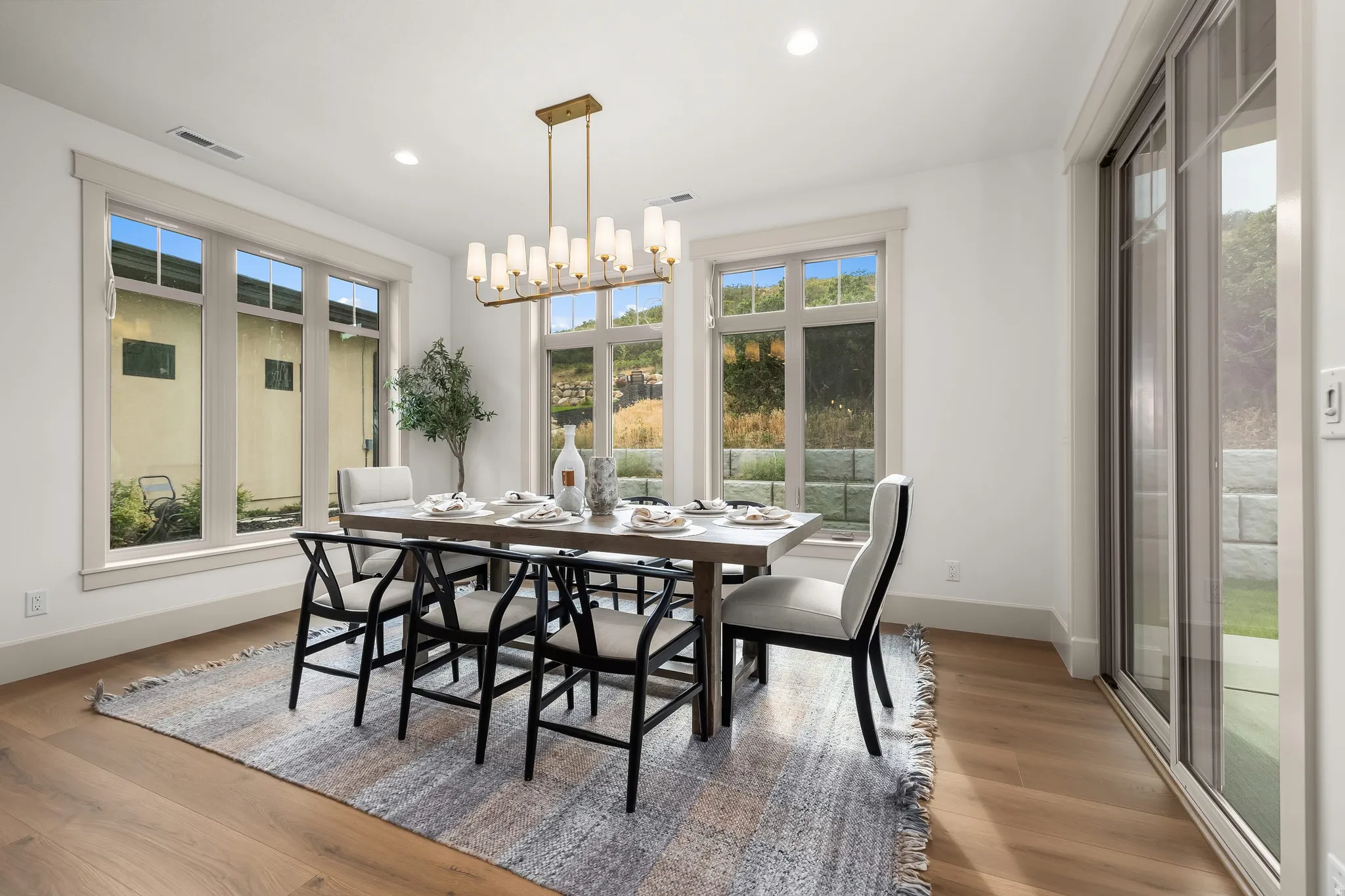 Recessed lighting, wood-finish flooring, multiple windows with trim, sliding glass door, and a modern chandelier