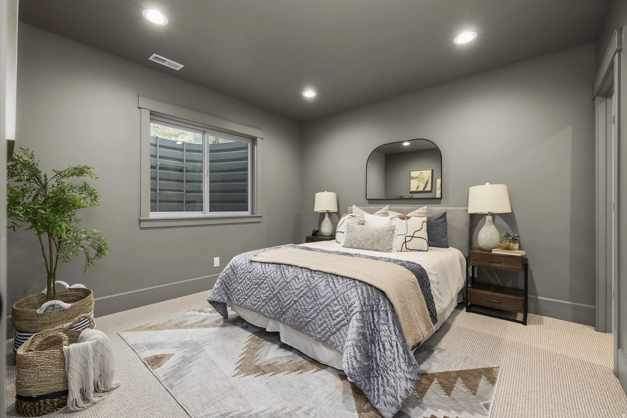 Recessed ceiling lighting, carpet flooring, window with white trim, gray painted walls, and an arched wall mirror