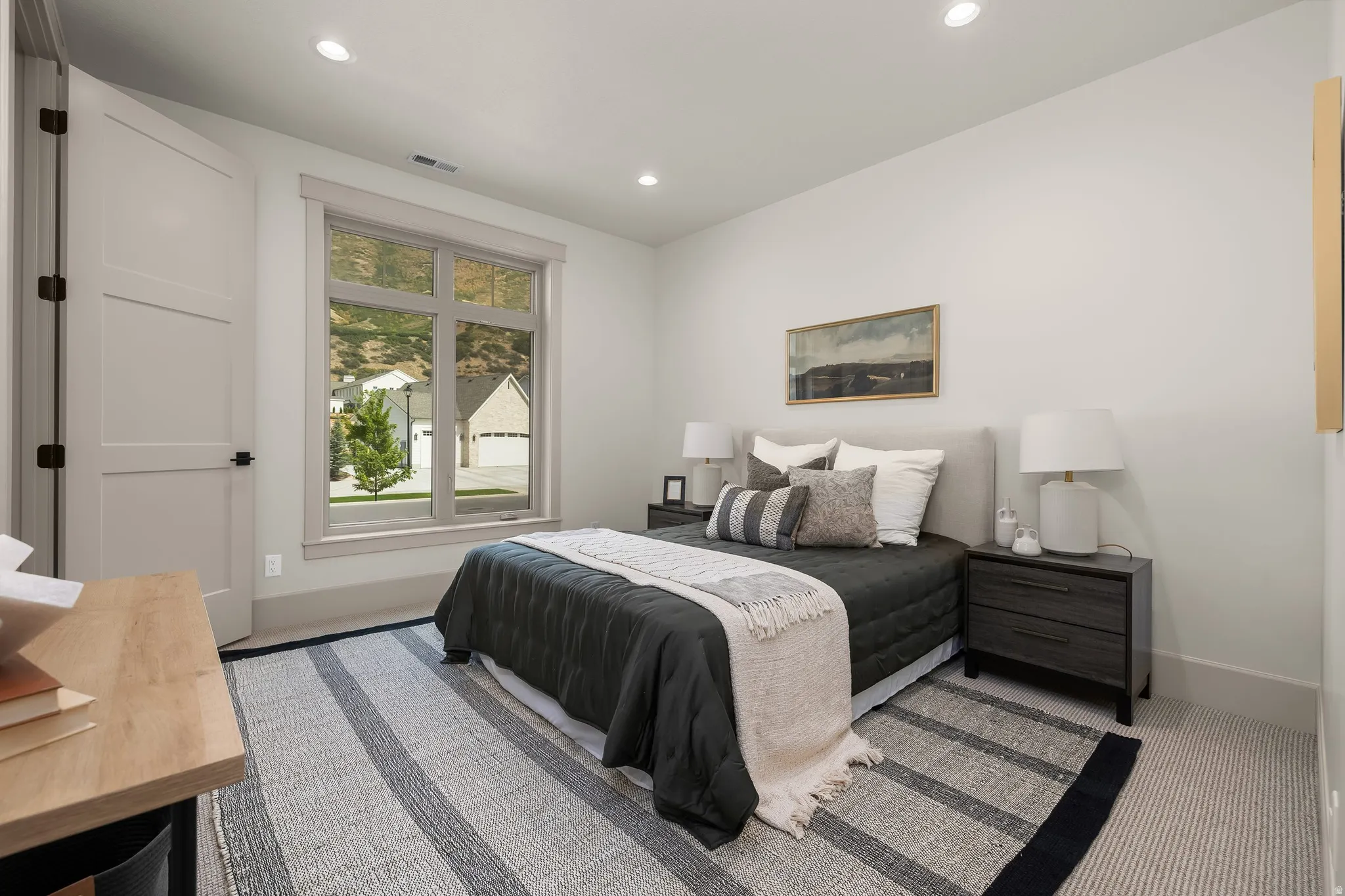 Recessed lighting, light gray walls, window with light-toned trim, gray carpet flooring, and a neutral-toned door