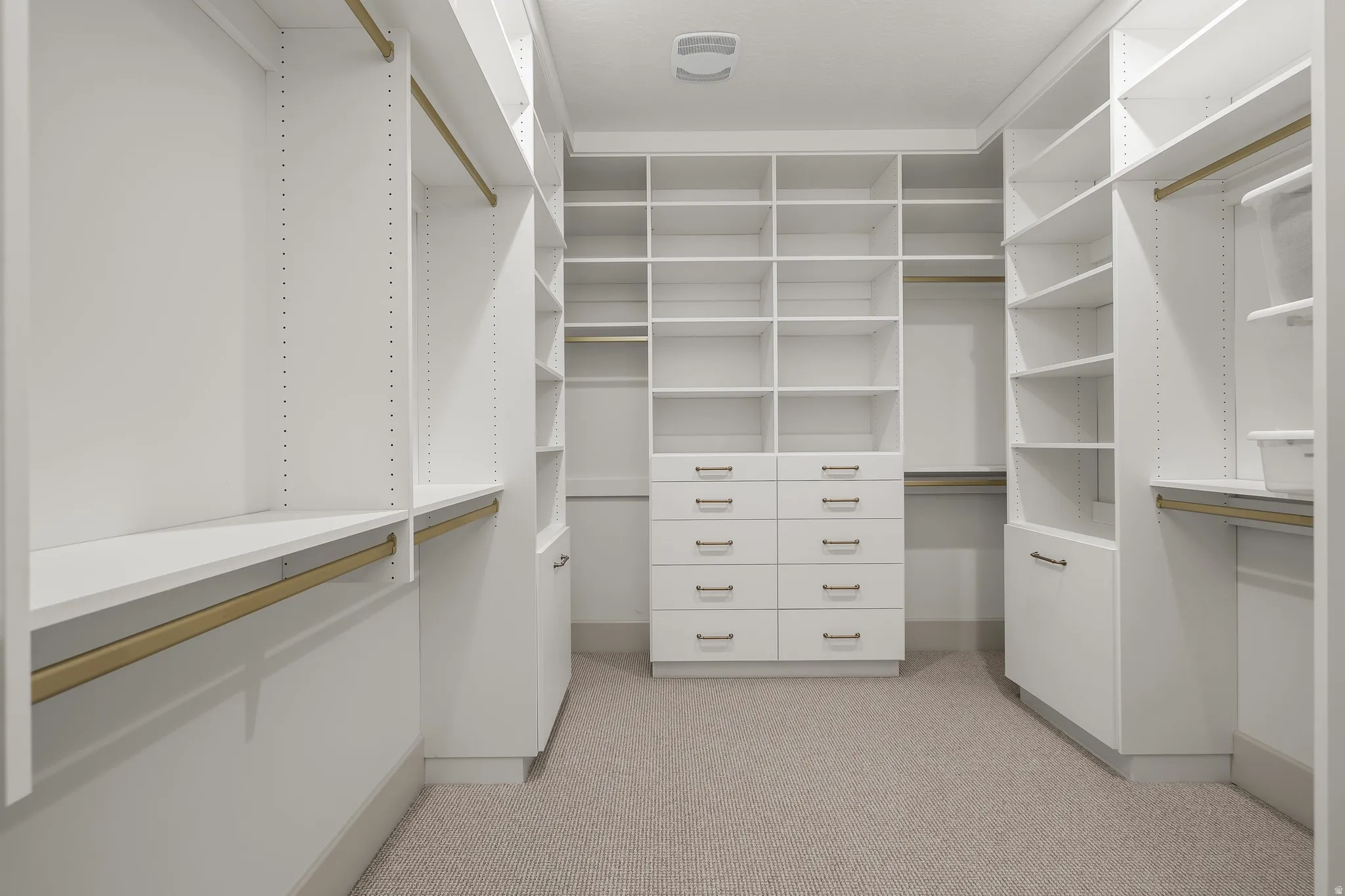 Walk-in closet featuring extensive built-in shelving, multiple hanging rods, and integrated drawer storage with brushed nickel hardware