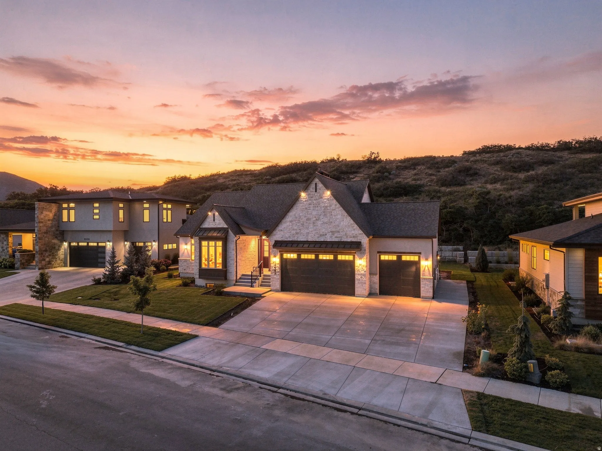 Stone and stucco exterior with multiple gables, a three-car garage, and landscaped grounds