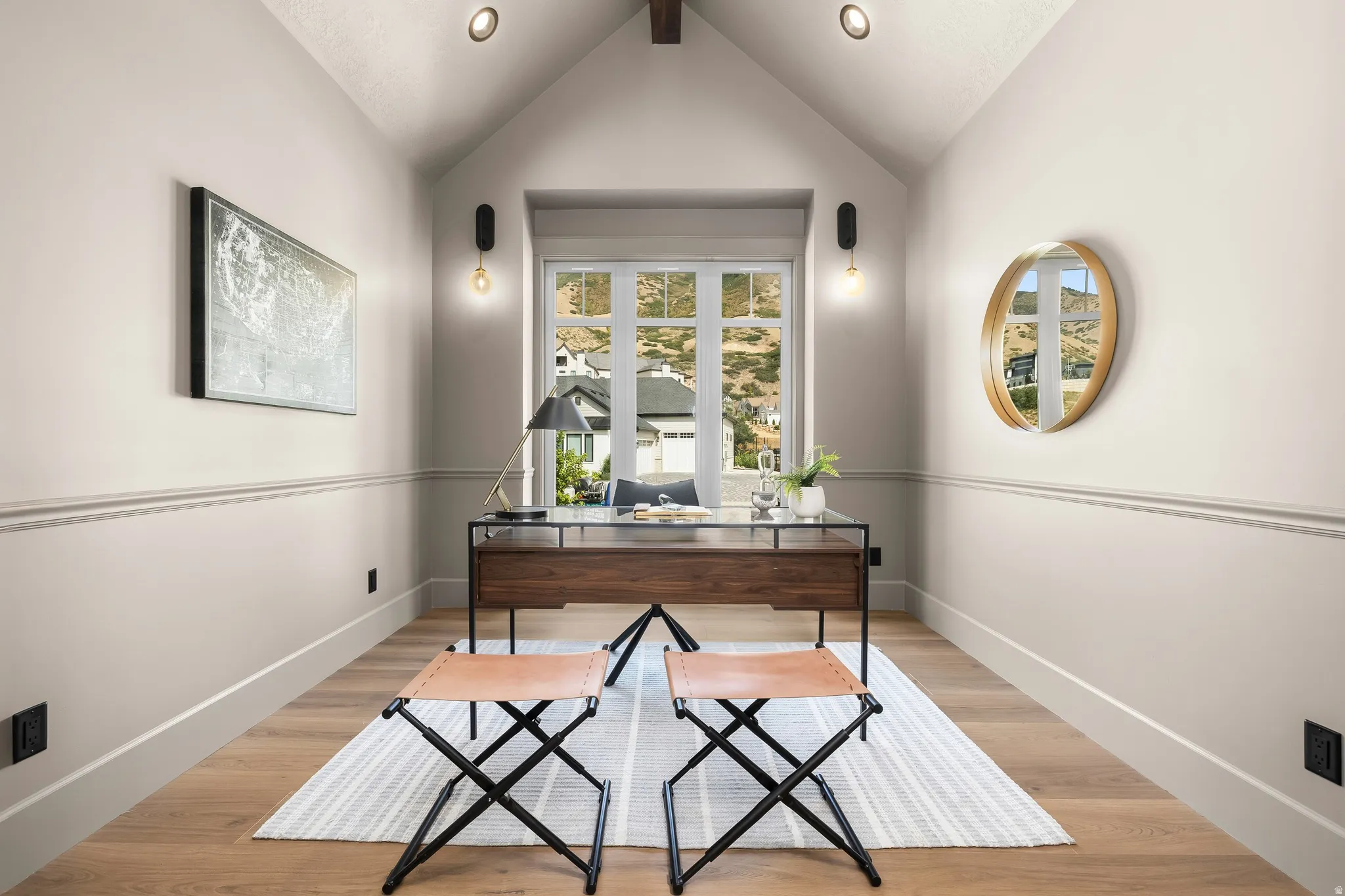 Vaulted ceiling with exposed wood beam, wood-finish flooring, and a window with mountain scenery