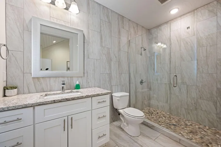 Bathroom featuring a full-width vanity with white cabinetry, a granite-finish countertop, and a rectangular undermount sink
