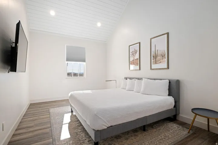 Bedroom featuring wood-finish flooring, a vaulted shiplap ceiling with recessed lighting, and a window with a roller shade