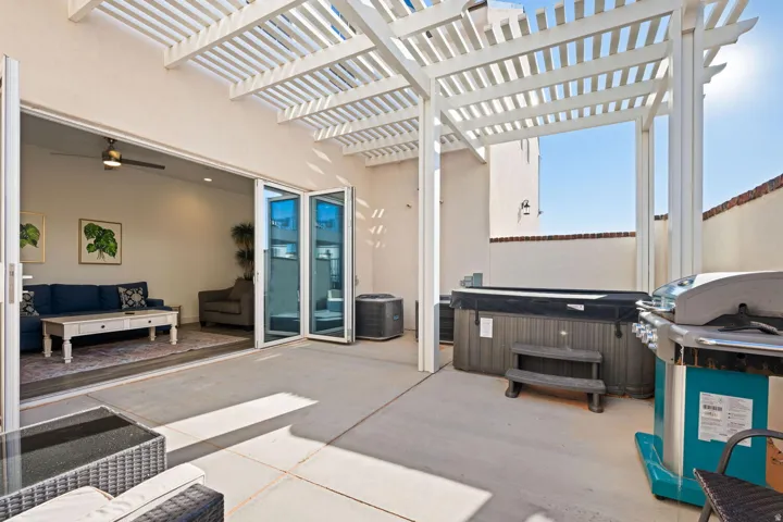 Spacious concrete patio featuring a white slatted pergola
