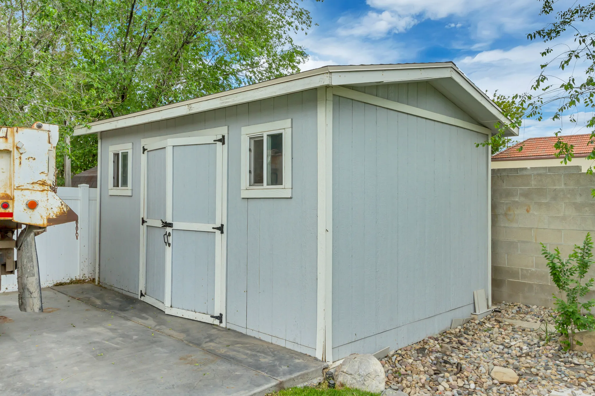 Utility shed with light blue siding, dual entry doors, and two fixed windows