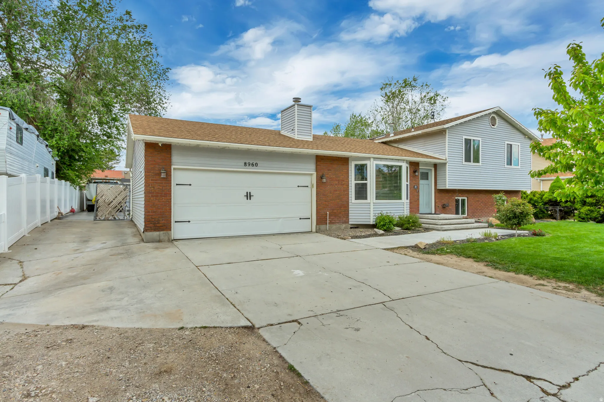 Split-level residence featuring a two-car garage with decorative hardware, brick and siding exterior, and a bay window