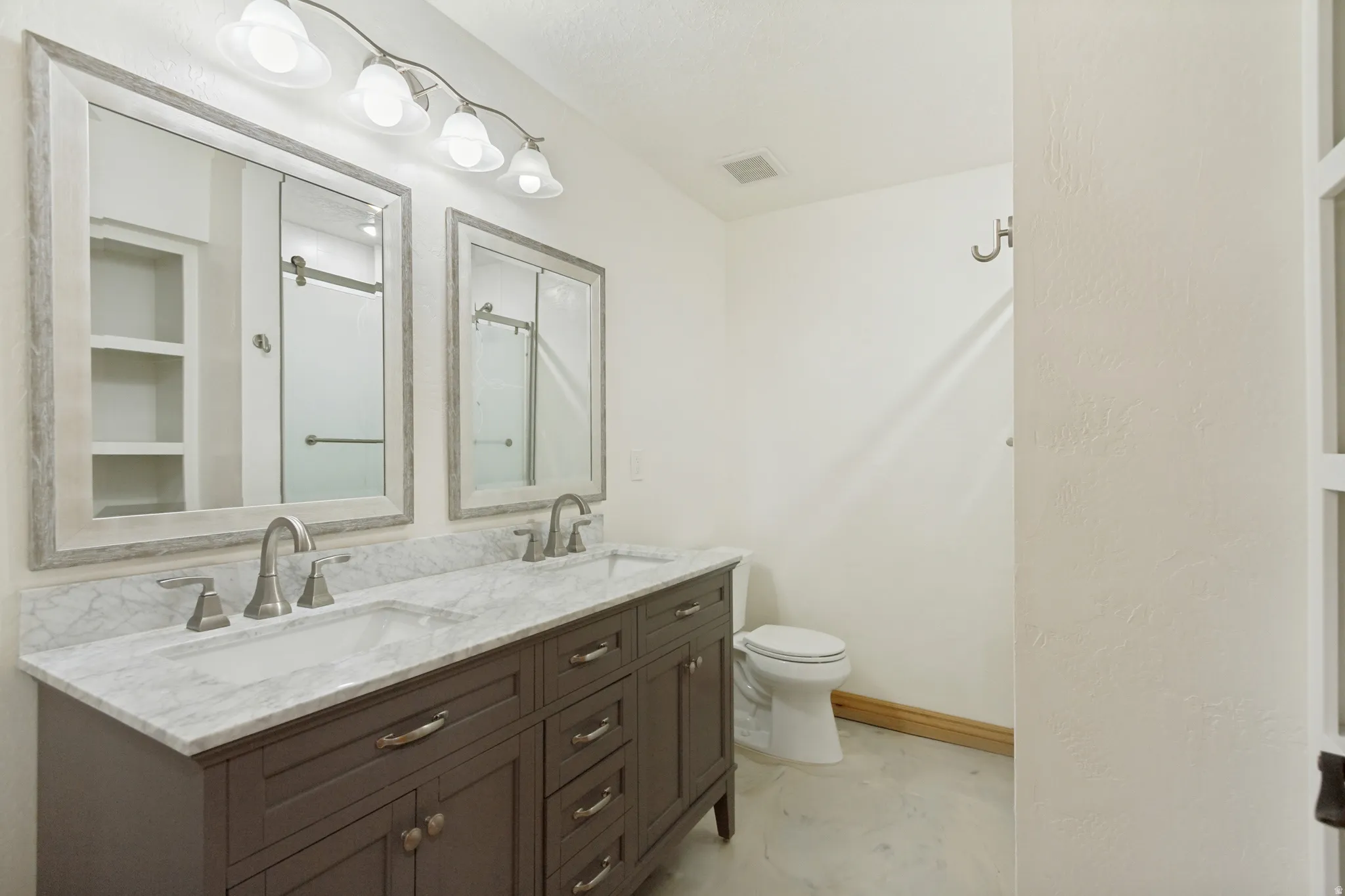 Double vanity featuring a white marble countertop, dual undermount sinks, and brushed nickel faucets