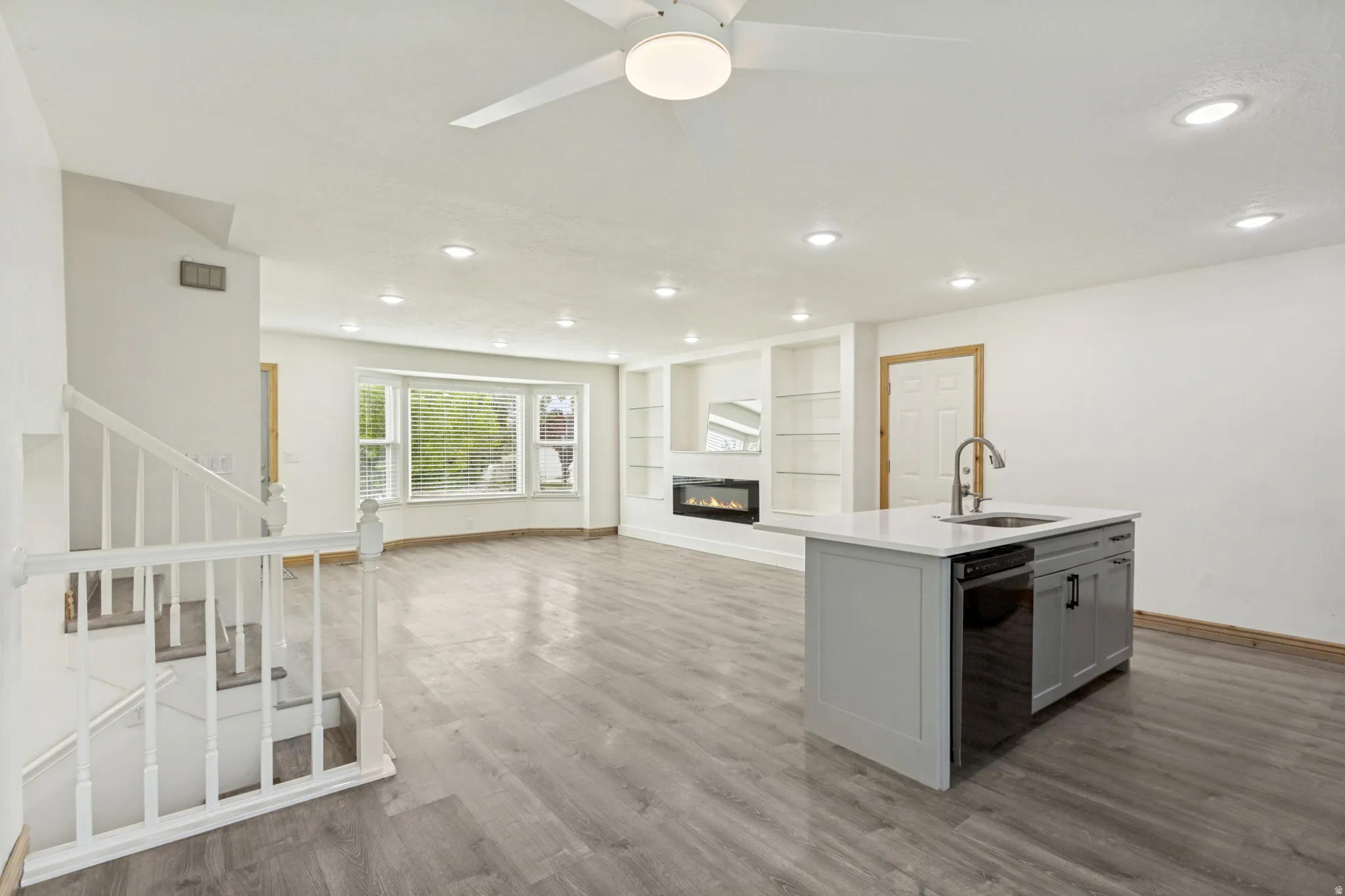 Open-concept living space featuring wood-finish flooring, recessed lighting, and a contemporary ceiling fan