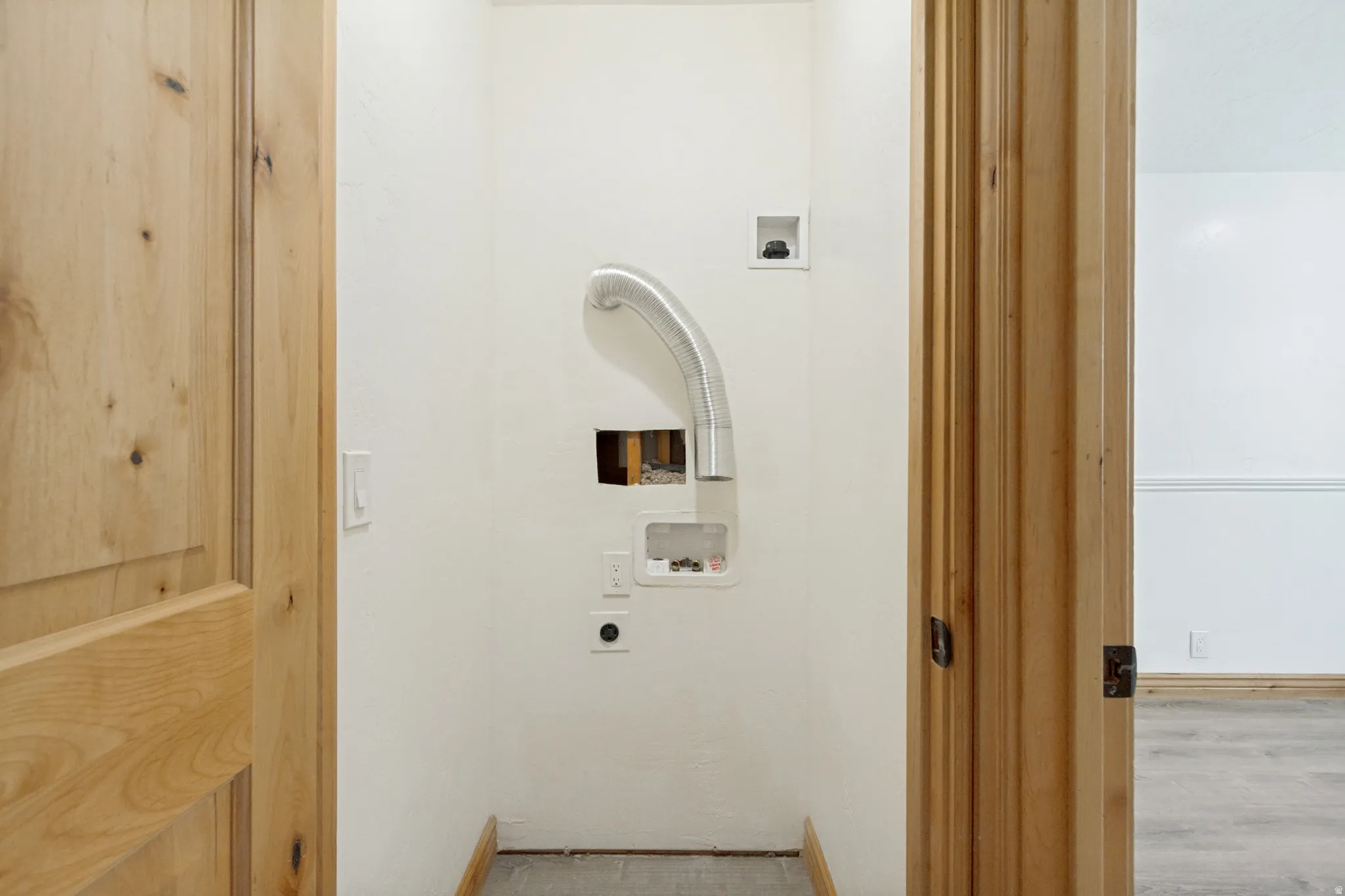 Utility area with appliance hookups, wood-finish flooring, and light wood doors