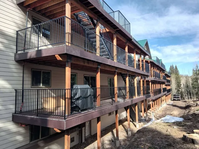 Multi-level property exterior with horizontal siding and multiple private balconies featuring black metal railings