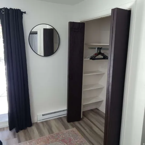 Closet featuring bi-fold doors, white shelving, and a hanging rod
