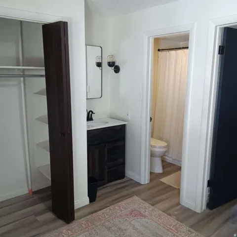 Vanity area with a dark wood-finish cabinet, white countertop, and a rectangular mirror with sconce lighting