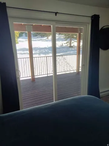 Sliding glass doors opening to an exterior deck with dark wood-finish decking and metal railings