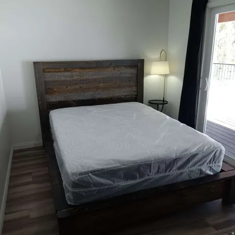Bedroom featuring wood-finish flooring, white walls, and a sliding glass door leading to an outdoor deck
