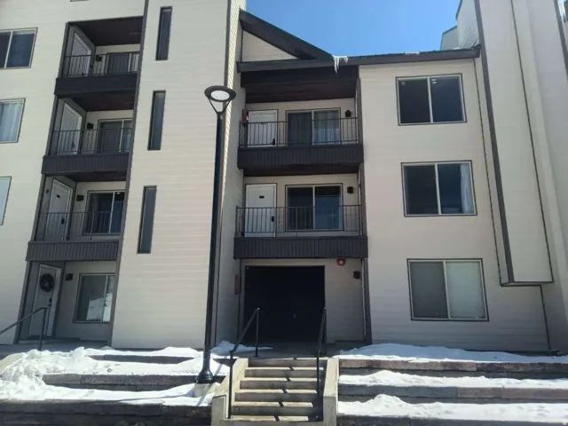 Multi-story residential building with light-colored siding and dark trim