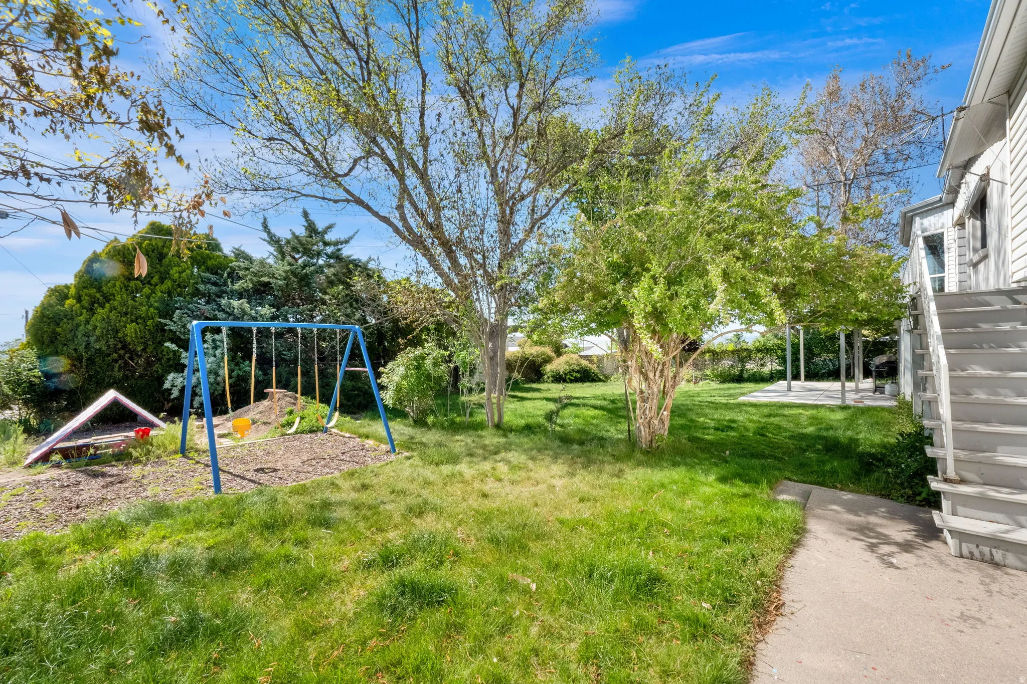 Expansive green lawn with mature trees and a concrete patio