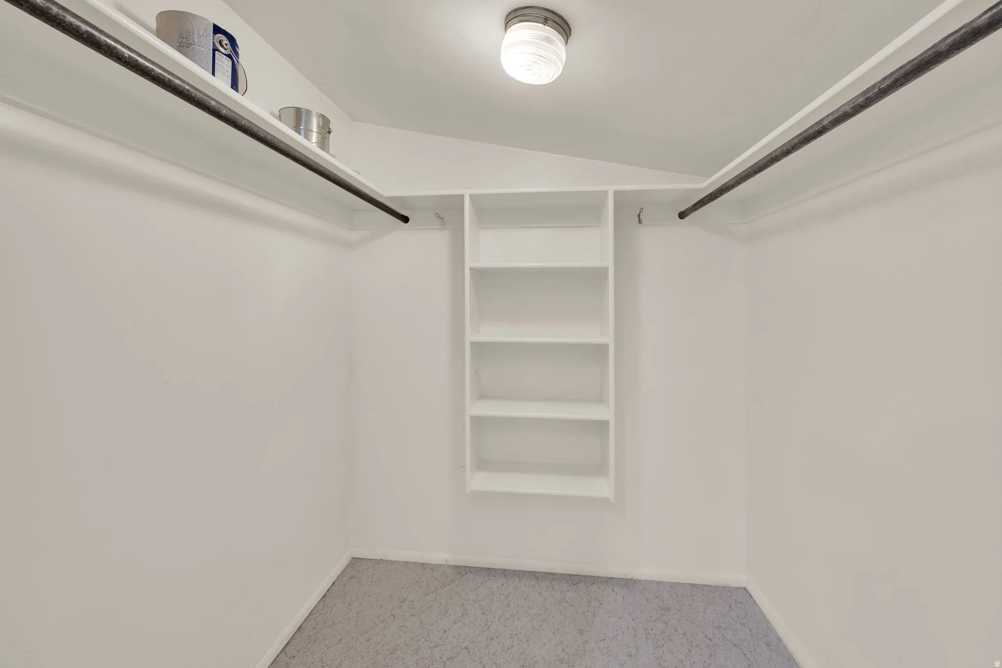 Walk-in closet with built-in shelving, dual hanging rods, upper storage shelves, and overhead lighting