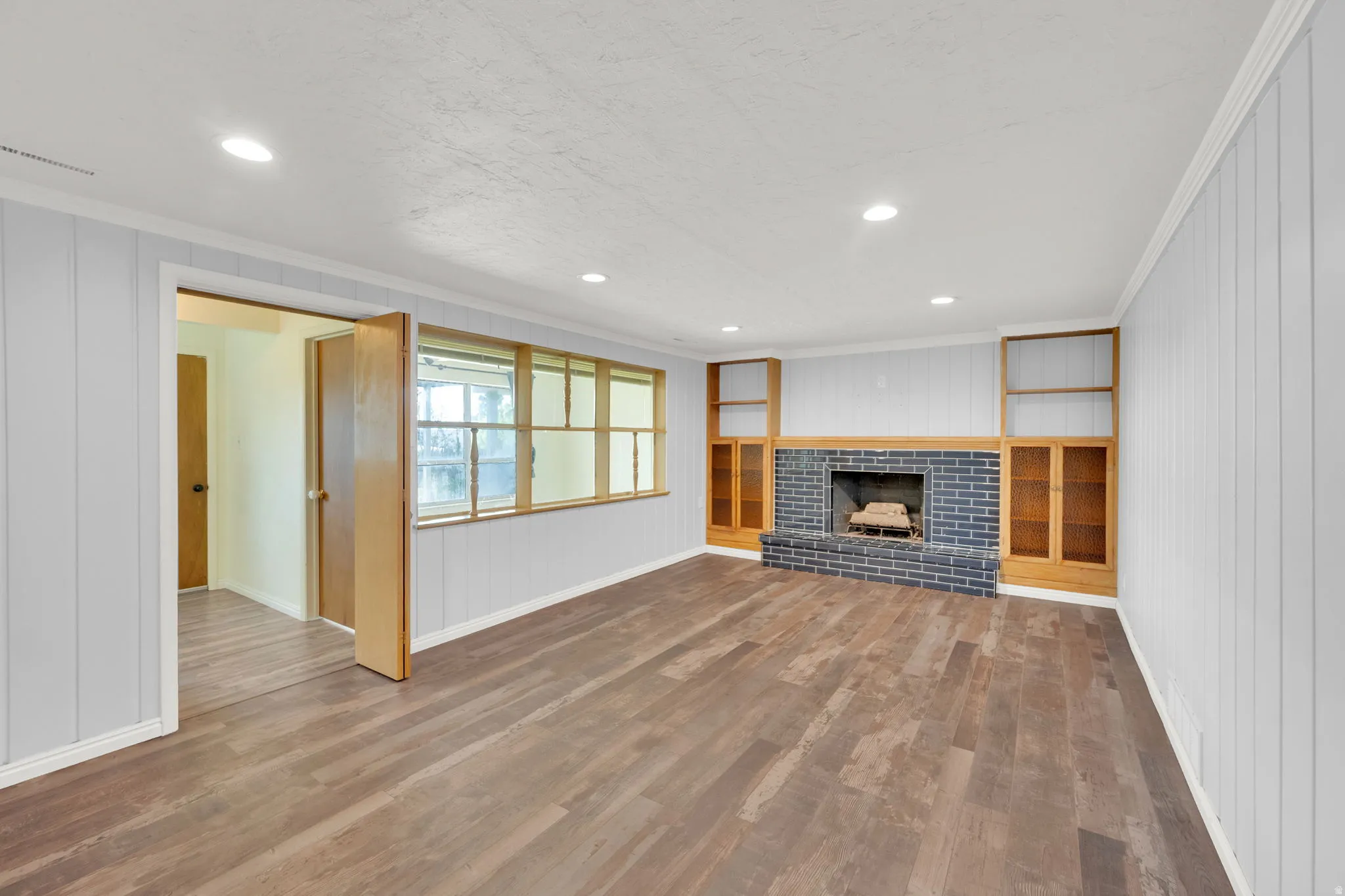 Spacious room featuring wood-finish flooring, recessed lighting, and white beadboard paneling