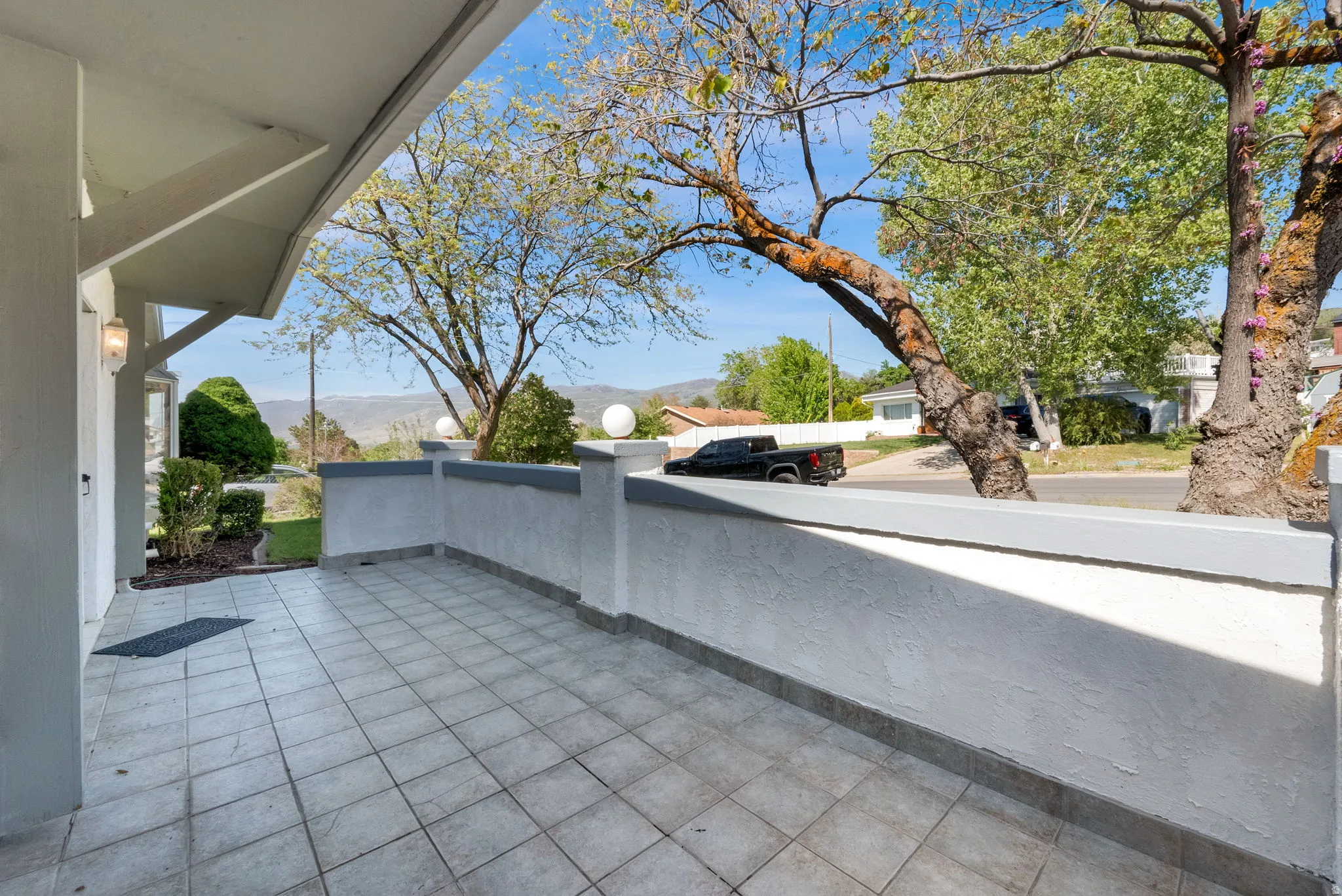 Tiled patio area featuring a low stucco wall and decorative spherical lights
