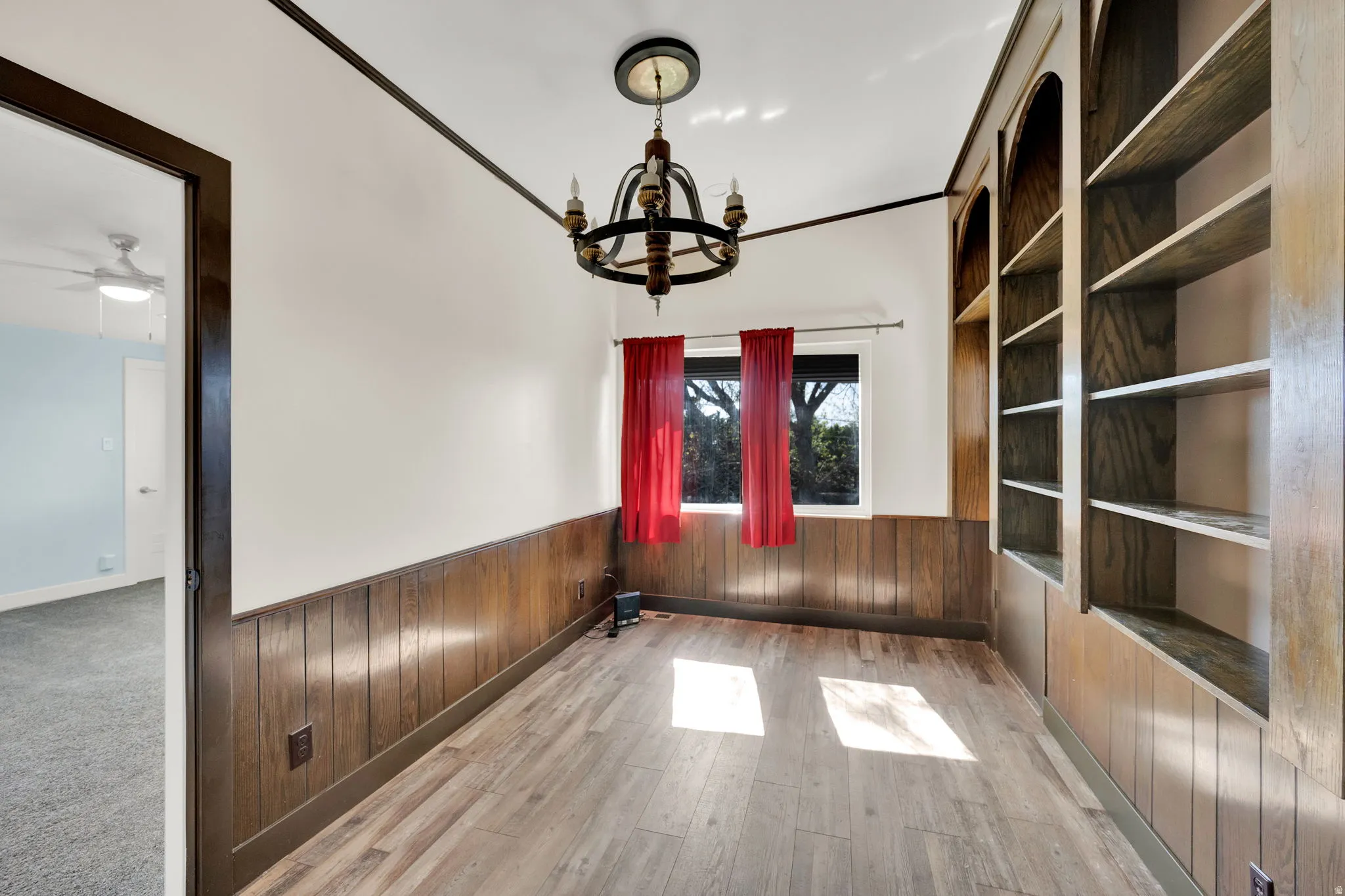 Interior space featuring wood-finish flooring, wainscoting, and a built-in shelving unit
