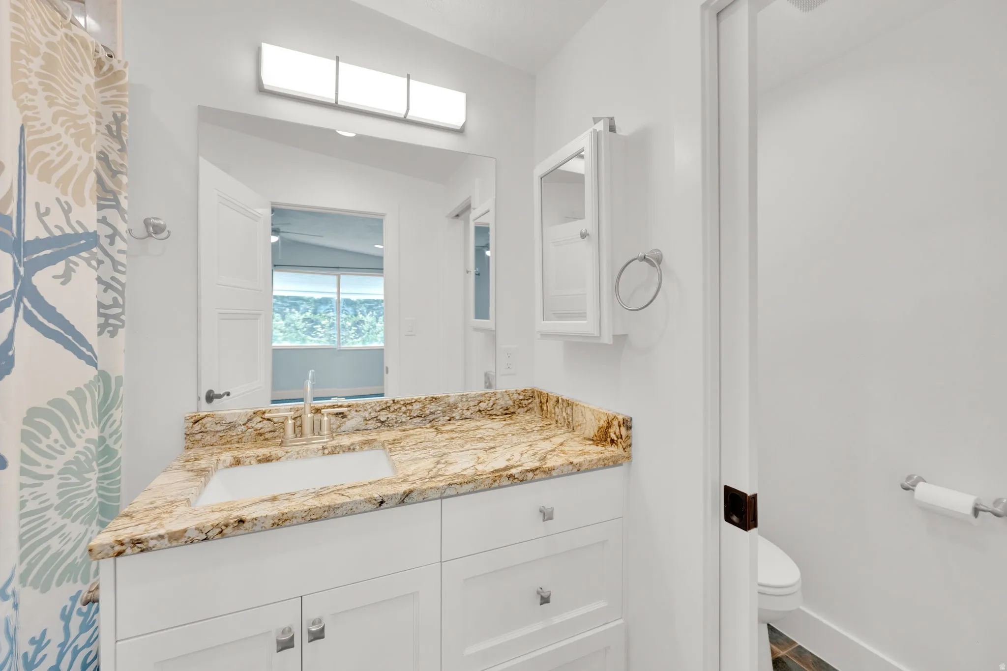 Bathroom vanity with a rectangular undermount sink, a polished chrome faucet, and a light-toned patterned countertop