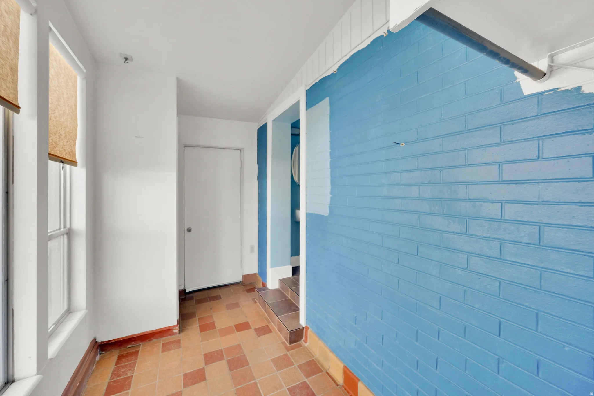 Interior brick wall with blue paint, contrasting with white wall finishes