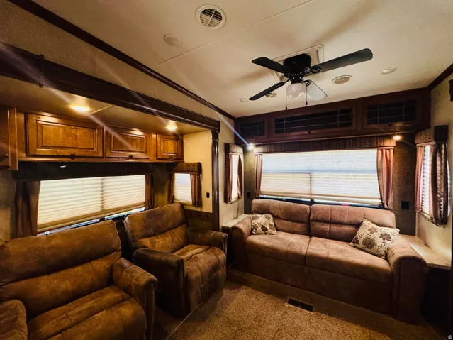 Living area featuring a ceiling fan with integrated lighting, recessed ceiling lights, and multiple windows with blinds and drapes