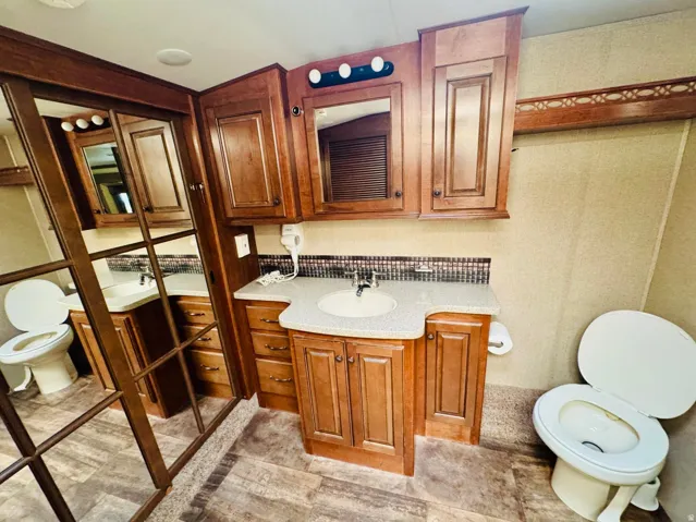 Bathroom featuring wood-finish cabinetry, dual vanities with integrated sinks, and coordinating laminate countertops