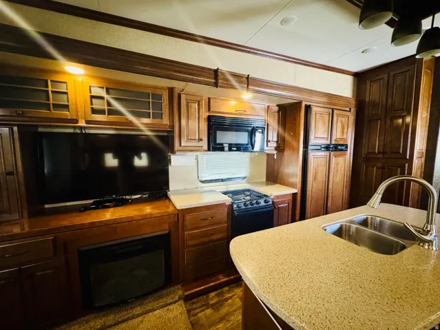 Kitchen and entertainment area featuring wood-finish cabinetry, a built-in electric fireplace, and a gas range