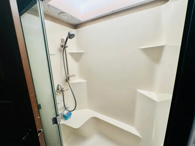 Fiberglass shower enclosure with integrated seating bench and multiple shelving units