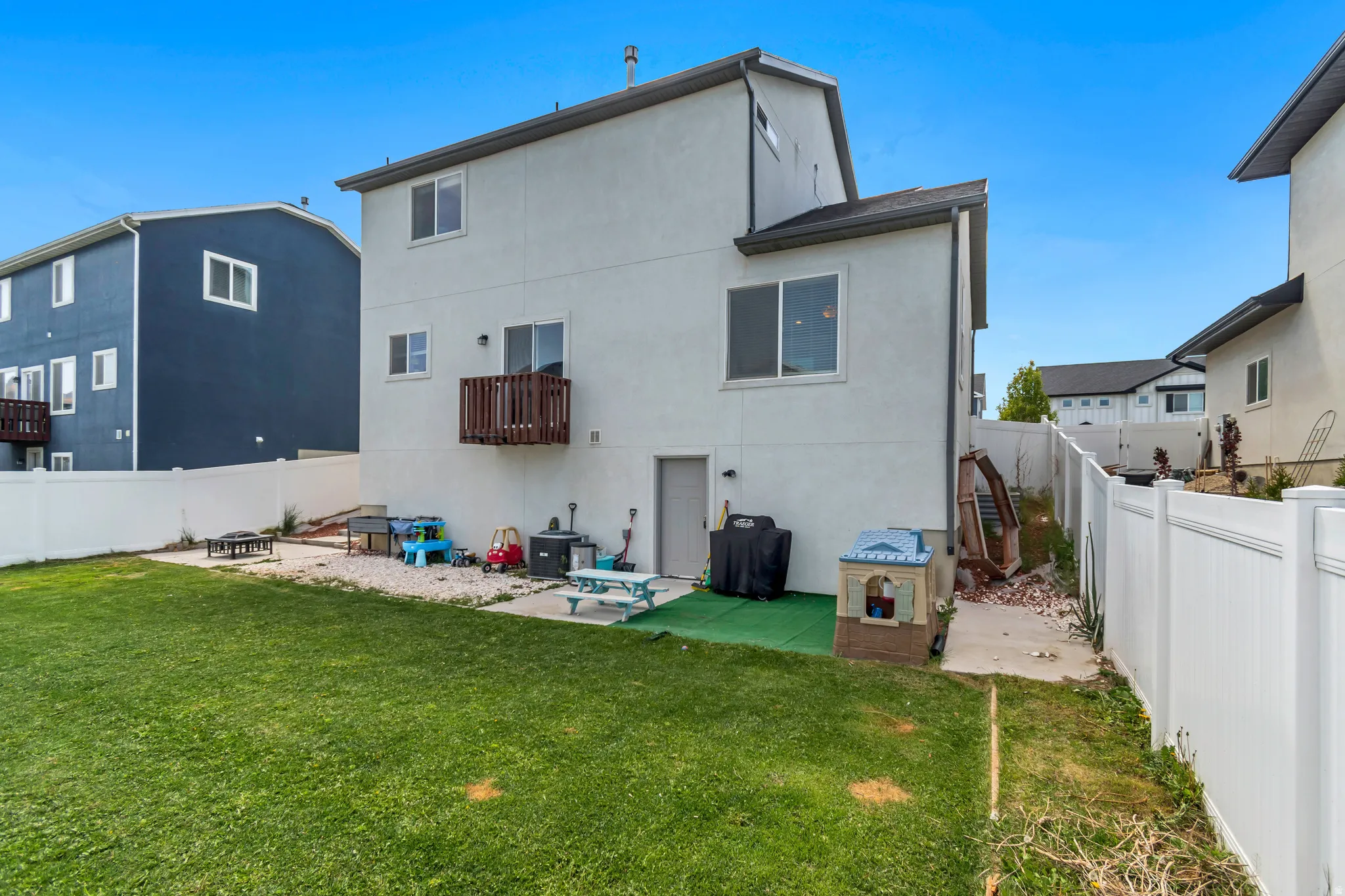 Expansive green lawn with a white vinyl fence enclosing the backyard