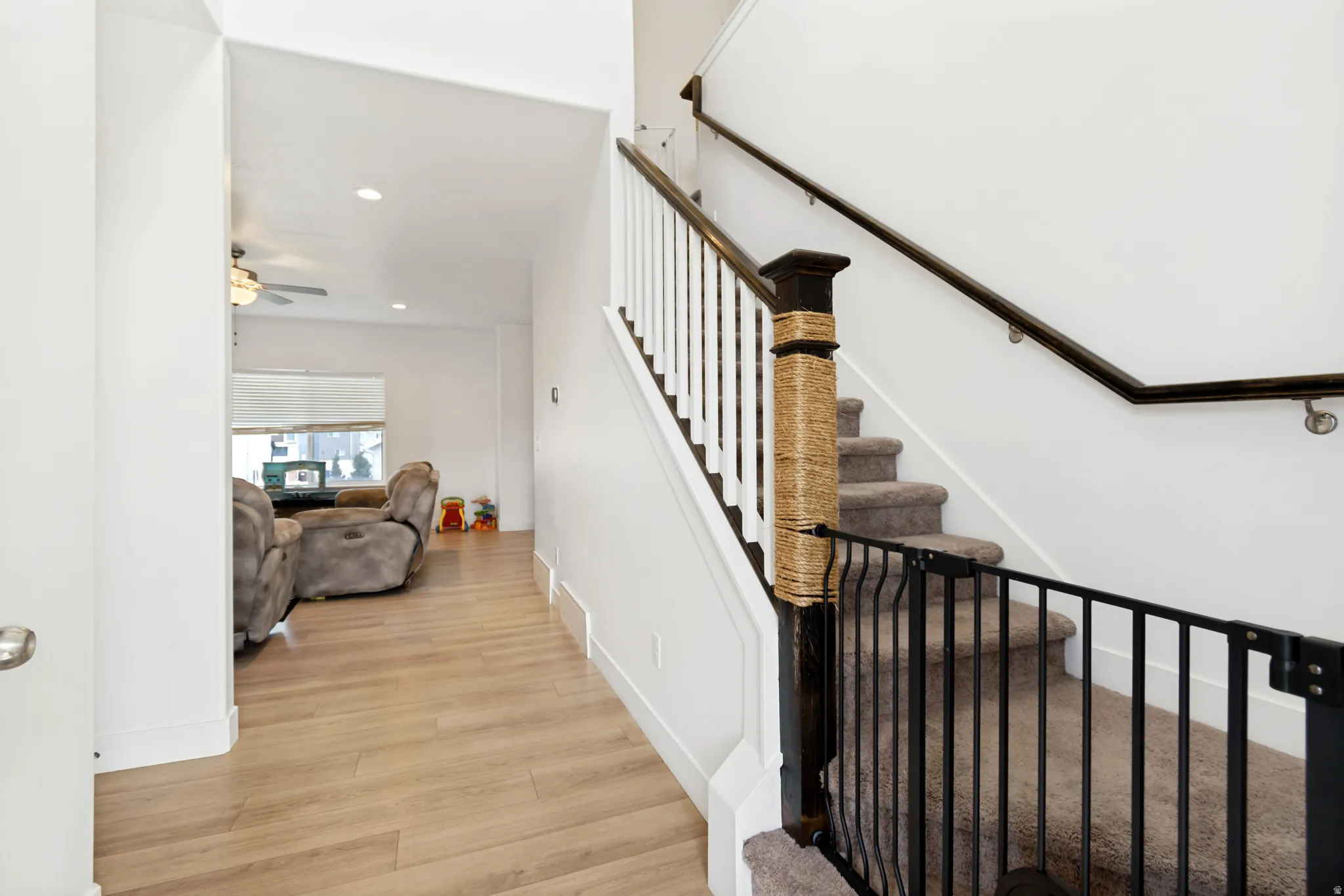 Staircase featuring white risers, carpeted treads, and a dark wood handrail with white balusters