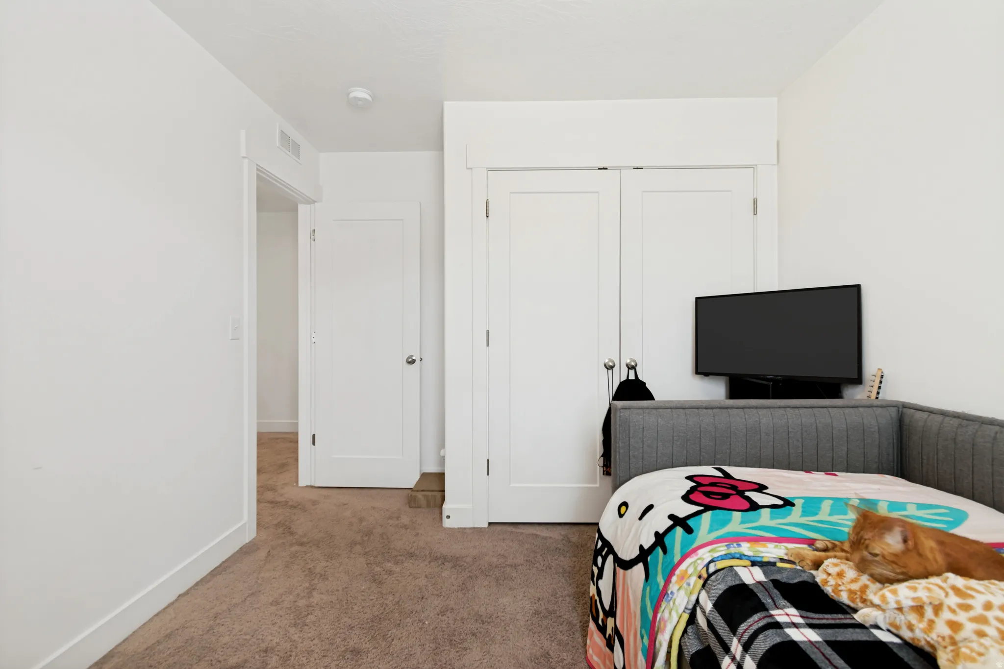 Bedroom featuring plush carpeting, white walls, and a built-in closet with double panel doors