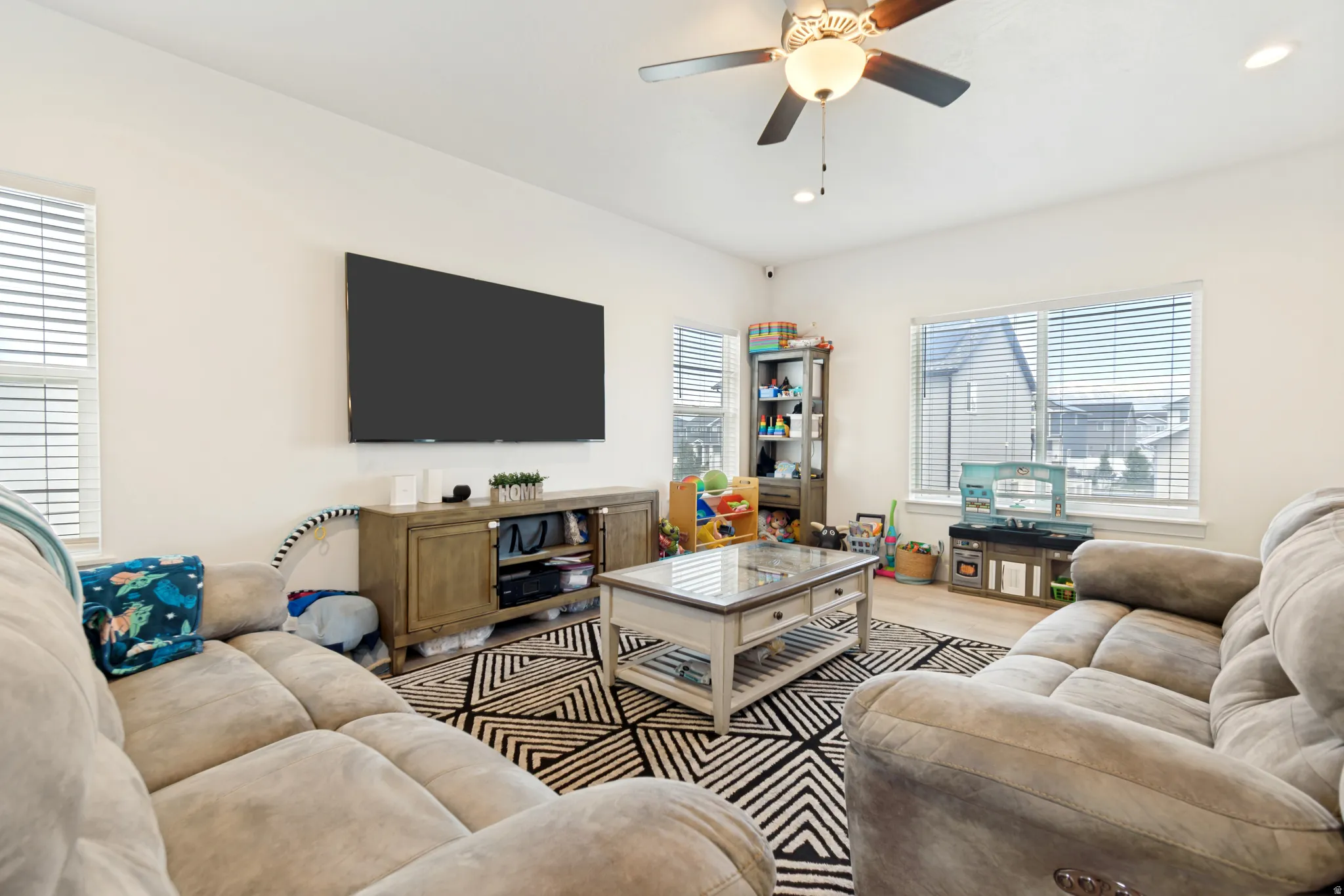 Open-concept living space featuring high ceilings, light wood-finish flooring, and ample natural light from multiple windows