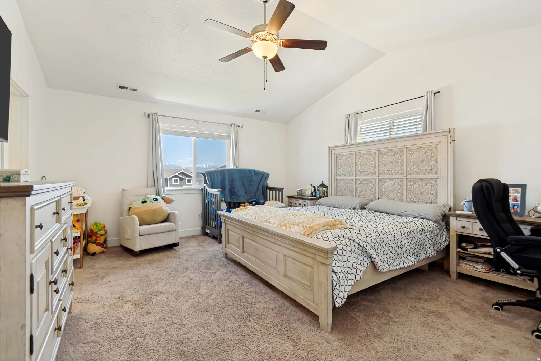 Spacious bedroom featuring vaulted ceilings, a ceiling fan with integrated lighting, and carpet flooring