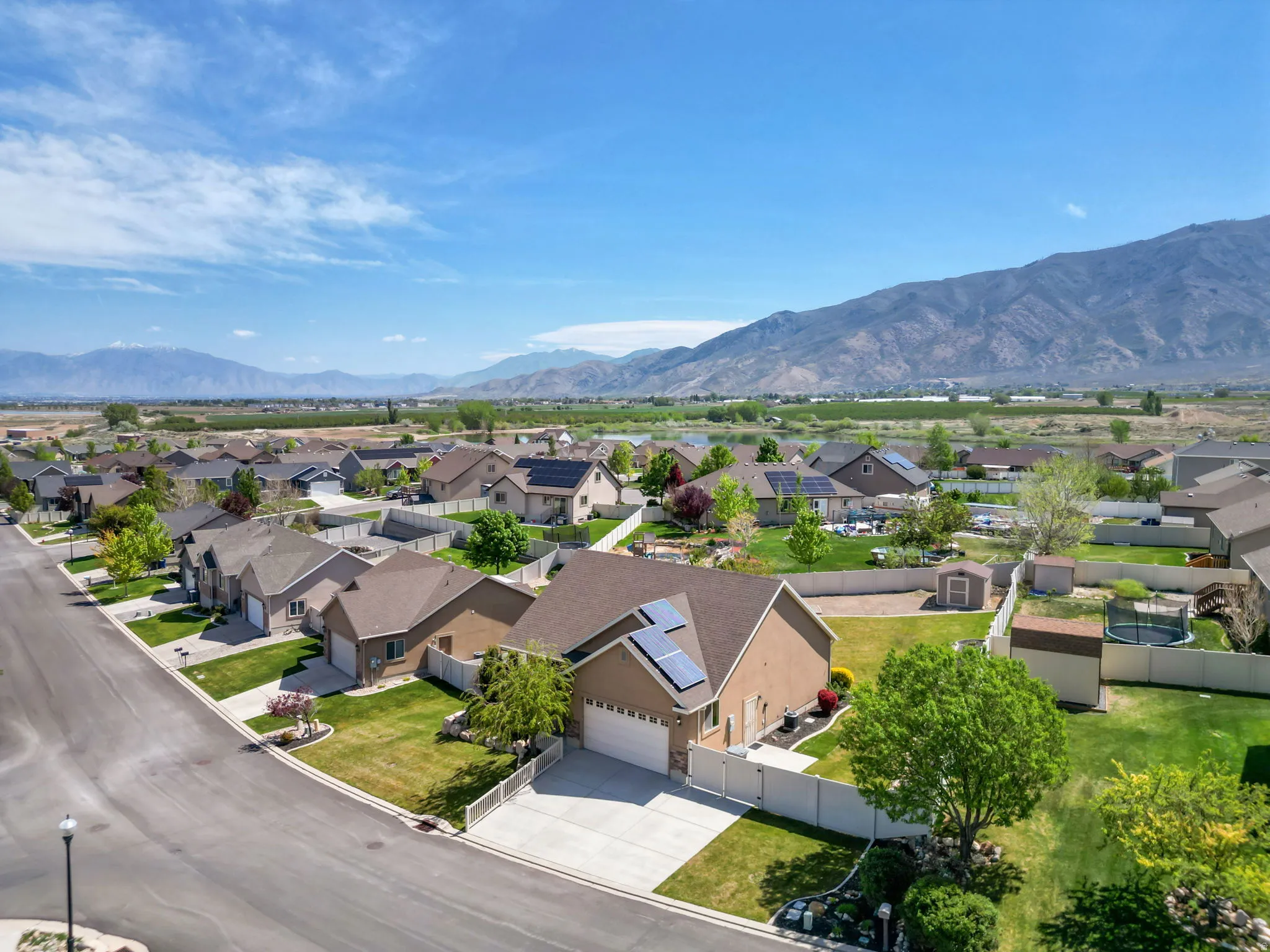 Residential neighborhood with a mountain backdrop, featuring single-story homes with attached garages, manicured lawns, and mature trees