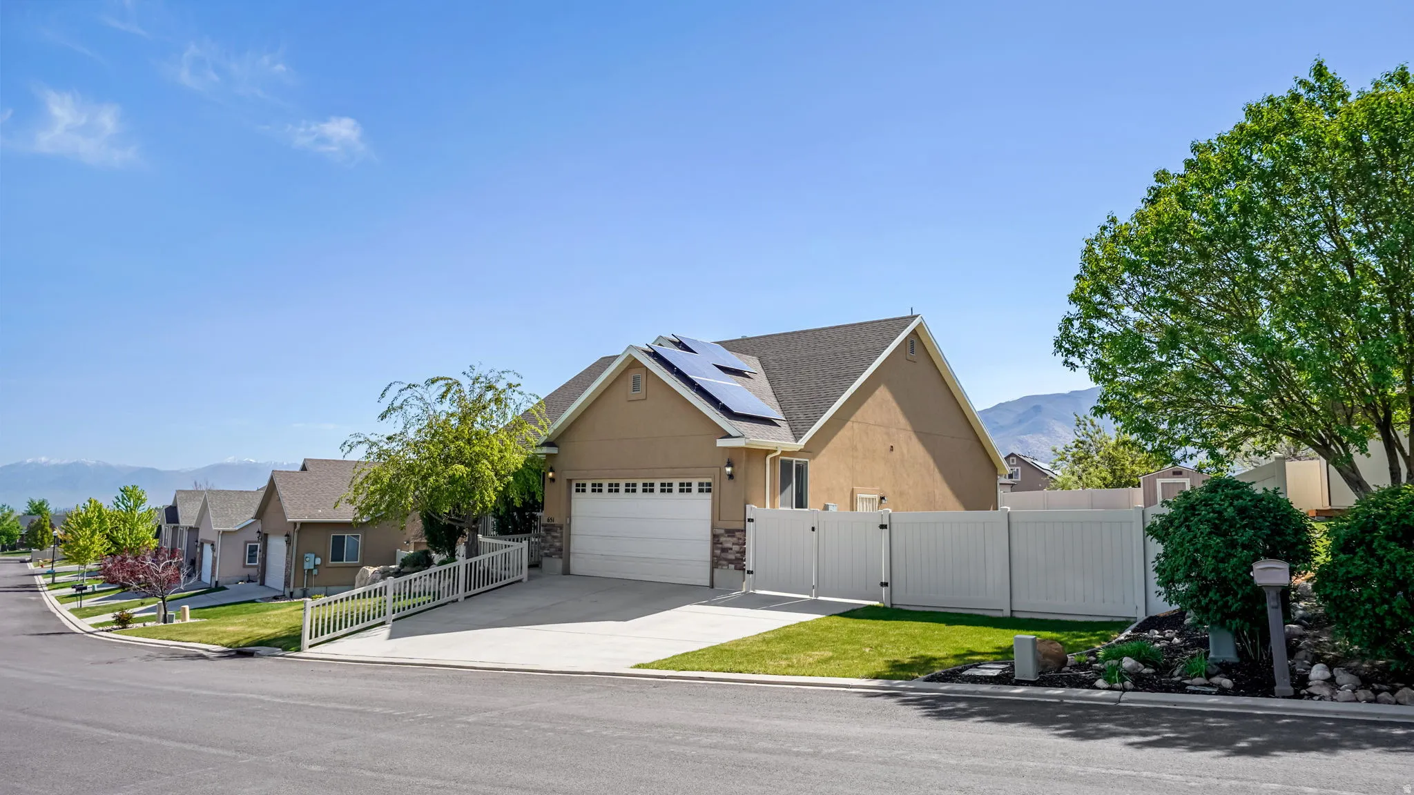 Single-story residence featuring a two-car garage, solar panels, and a concrete driveway