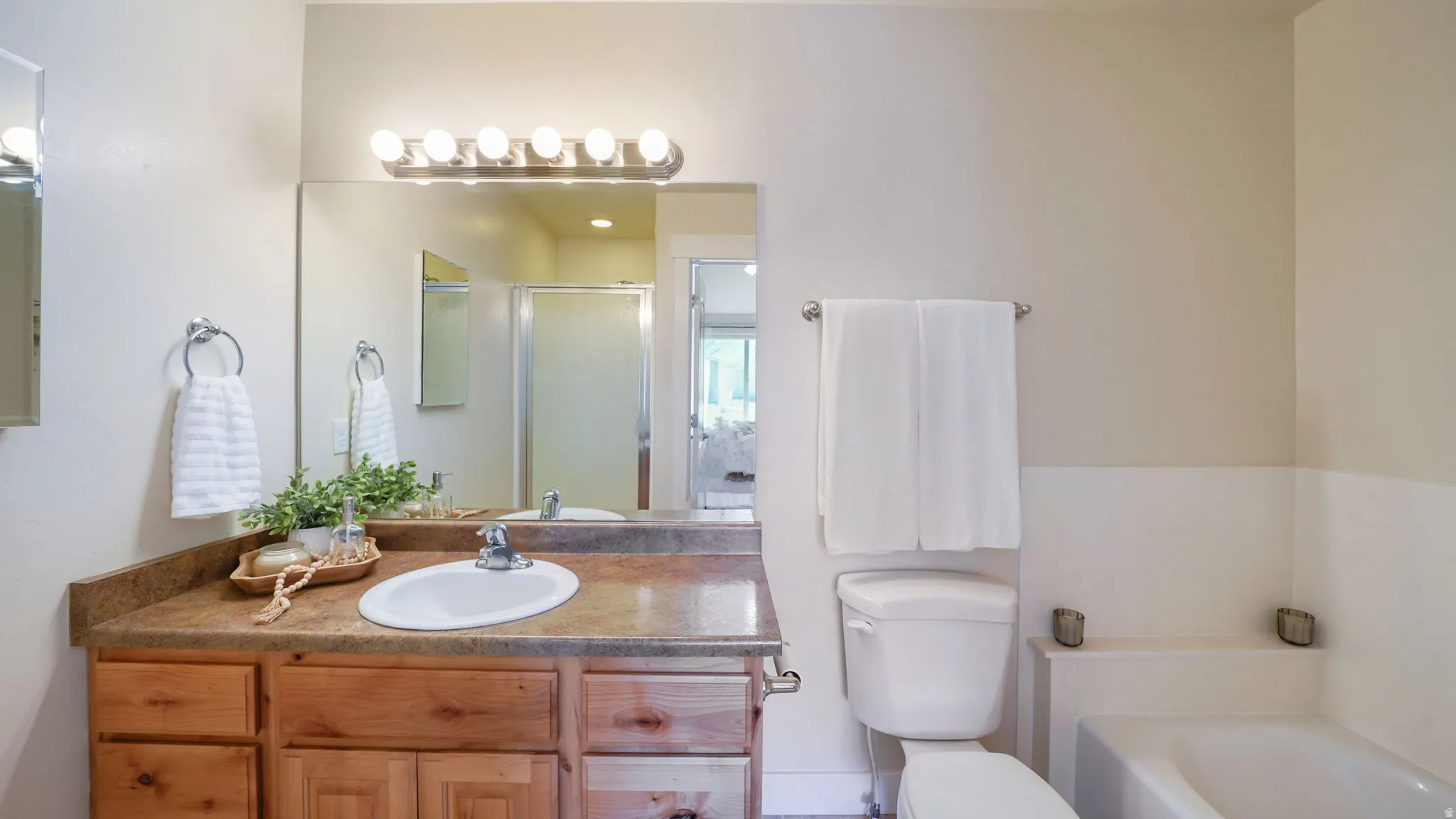 Bathroom featuring a single vanity with wood cabinetry, a light-toned countertop, and an undermount sink